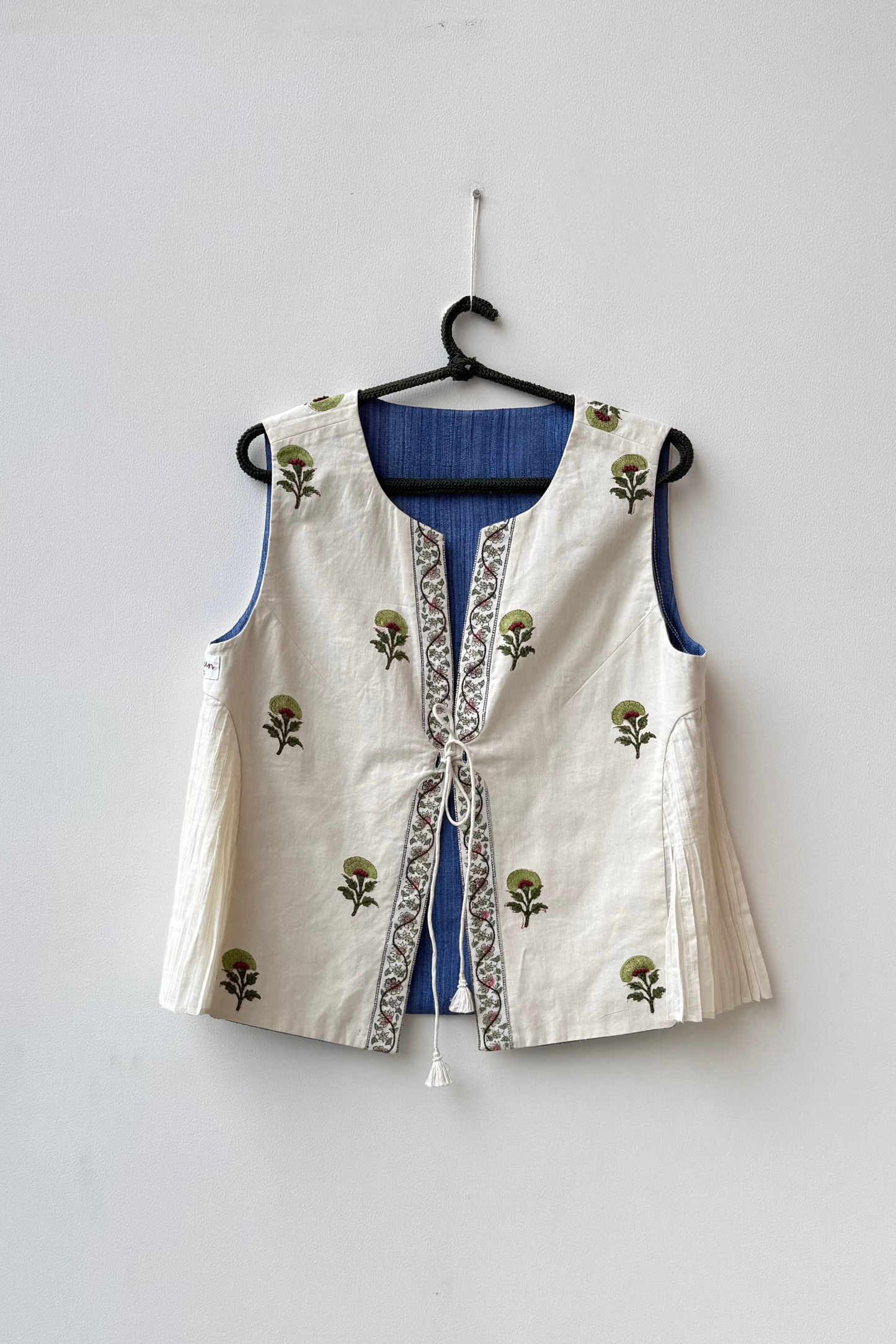 White embroidered vest with floral patterns on a hanger against a white background for Diwali & other festive occasions.