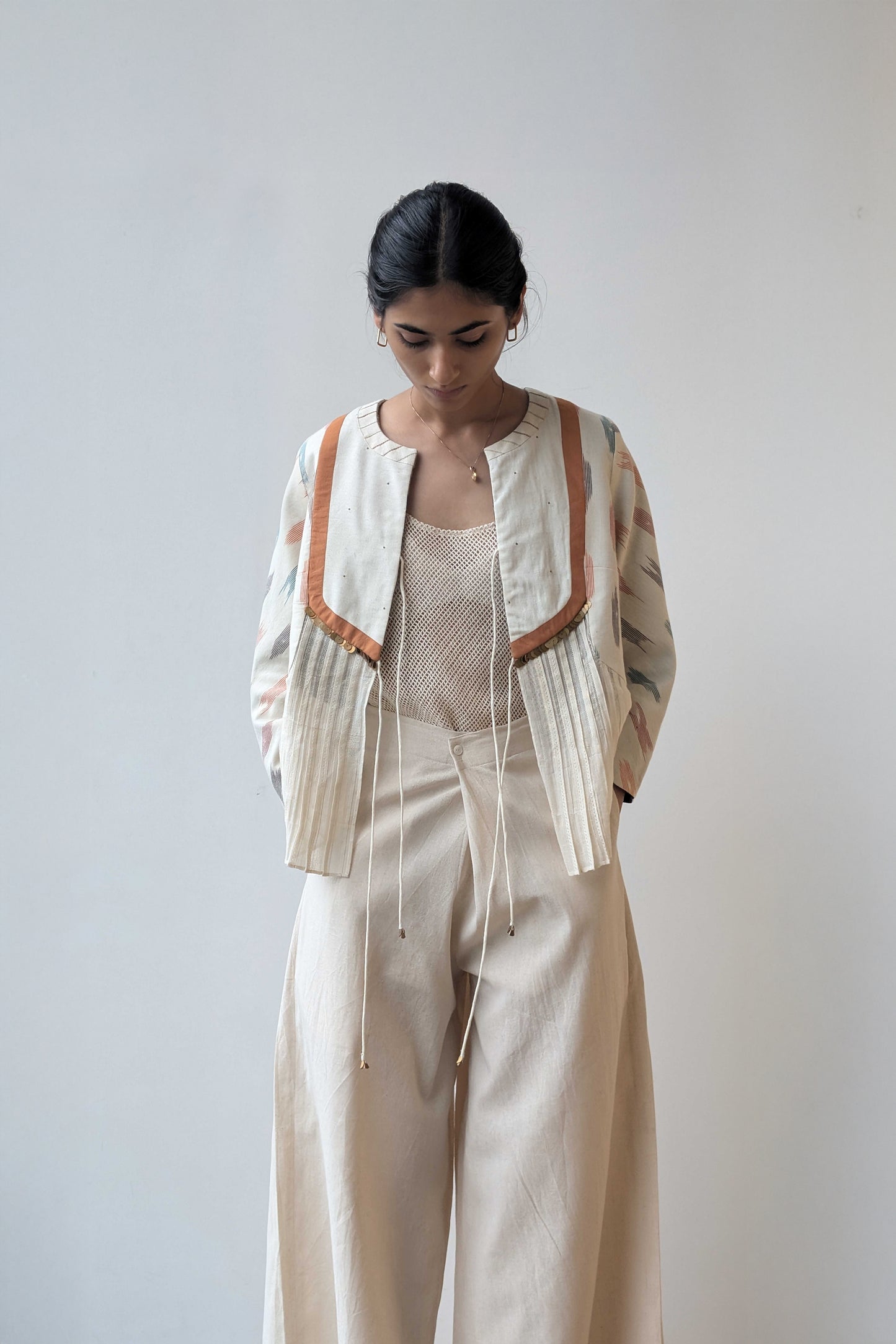 Woman wearing a reversible beige outfit with a patterned cardigan against a plain background for Diwali & festive occasions.