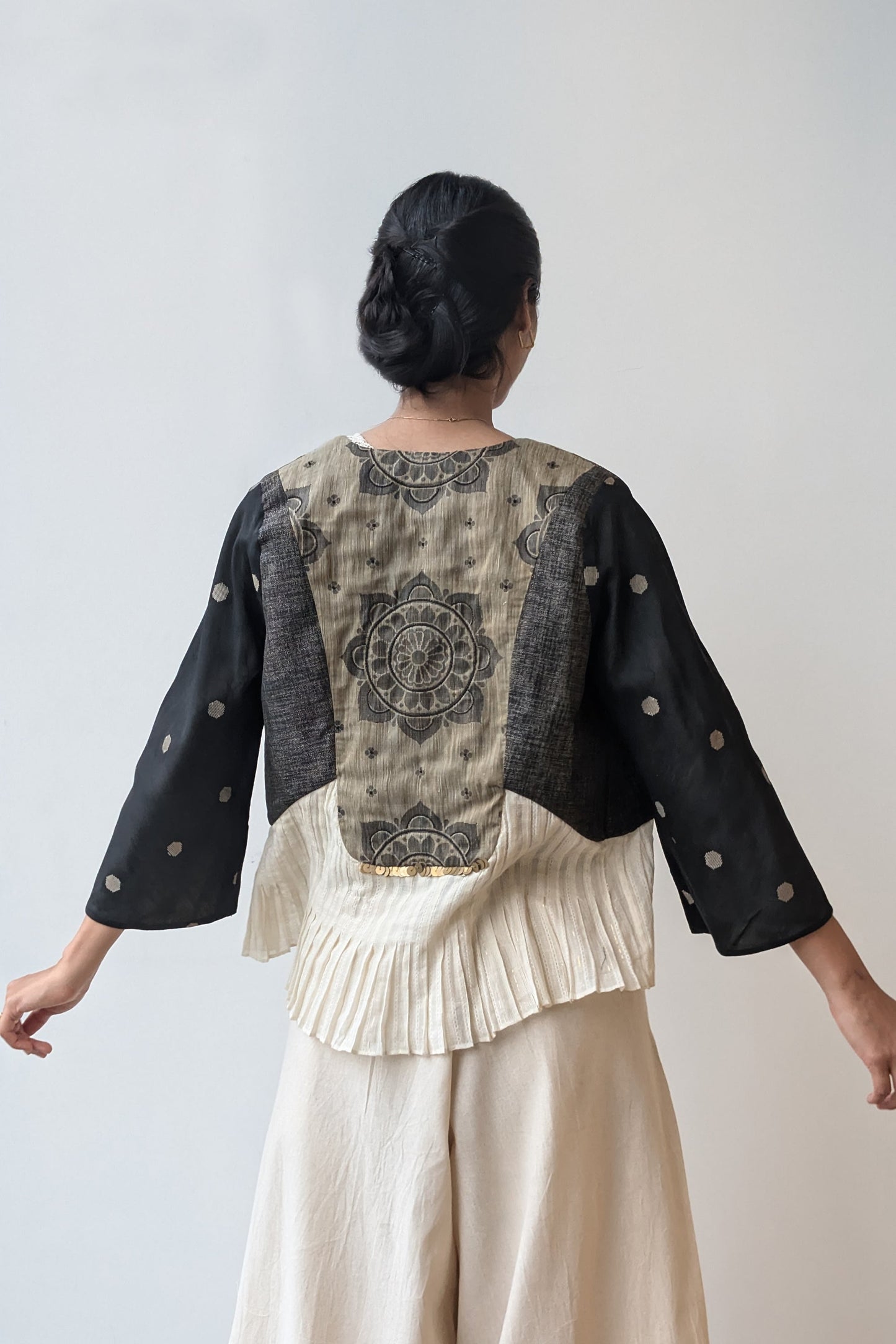Person wearing a reversible black and beige outfit with a brocade back design on a plain background for Diwali & festive occasions.