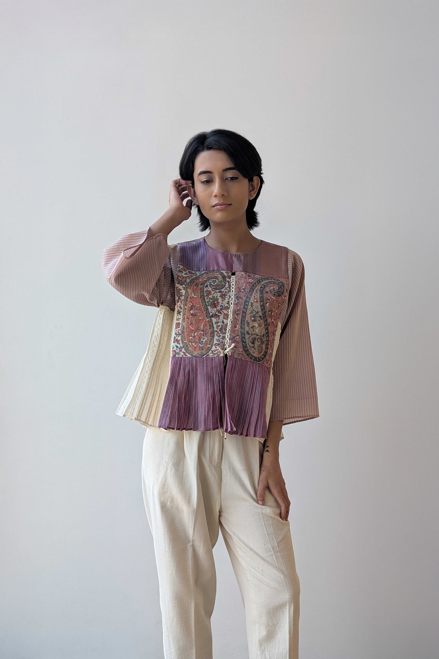 Person wearing a upcycled reversible, patterned top and beige pants against a plain background for Diwali & festive occasions.
