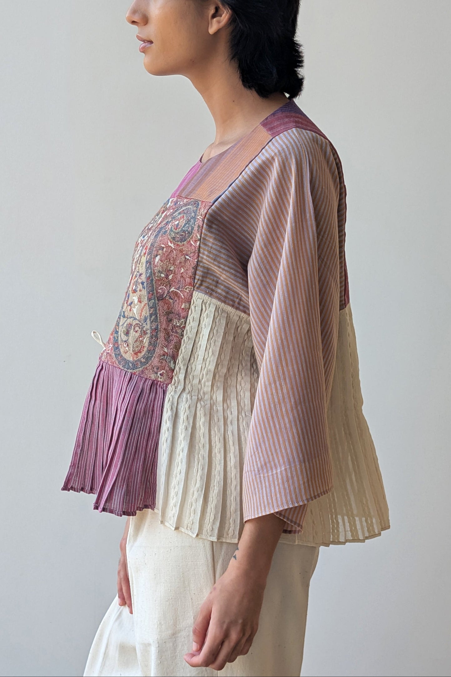 Woman wearing a reversible layered top and cardigan against a plain background for Diwali & festive occasions.