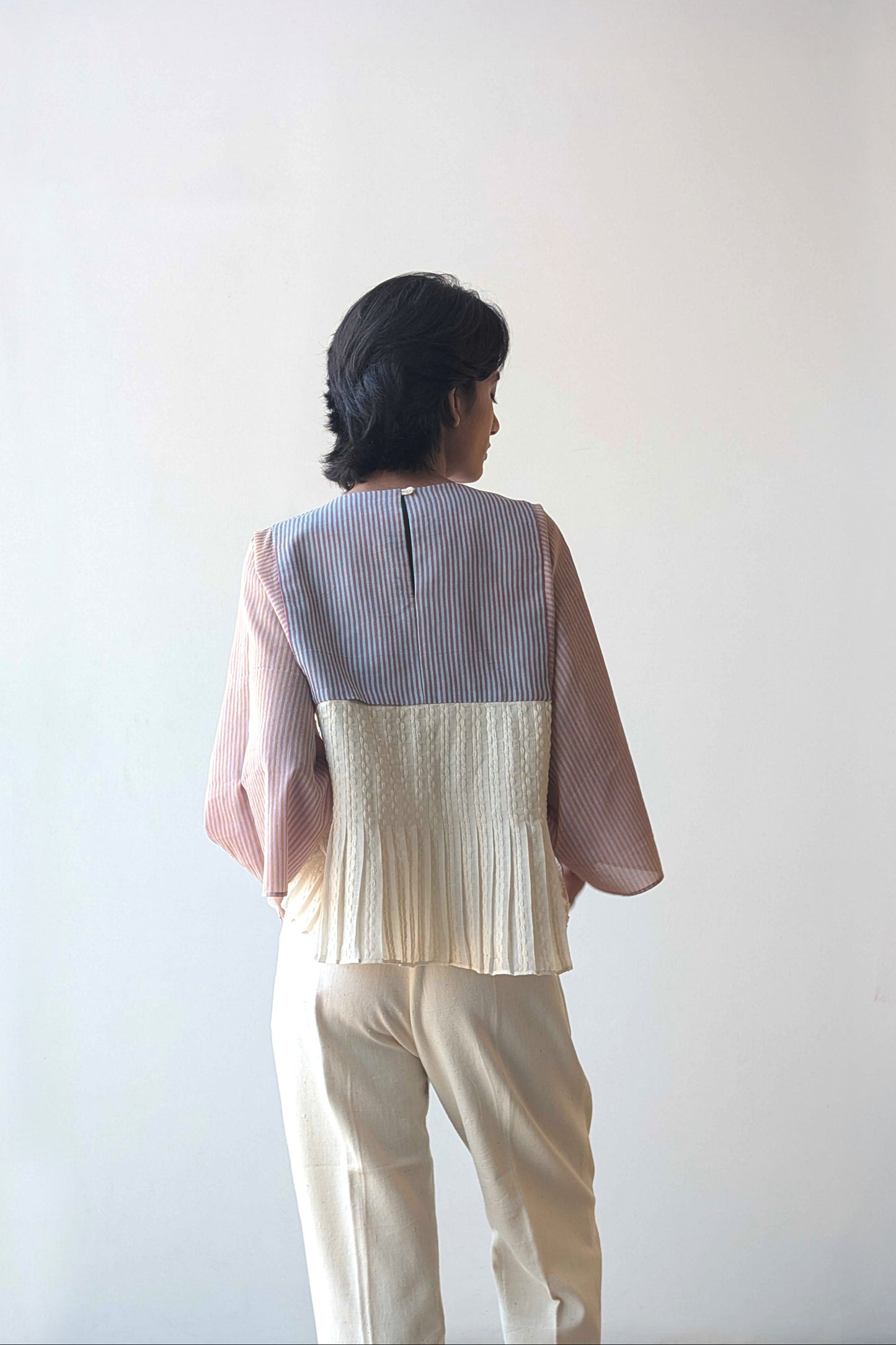 Person wearing a upcycled reversible two-tone top with a plain background for Diwali & festive occasions.