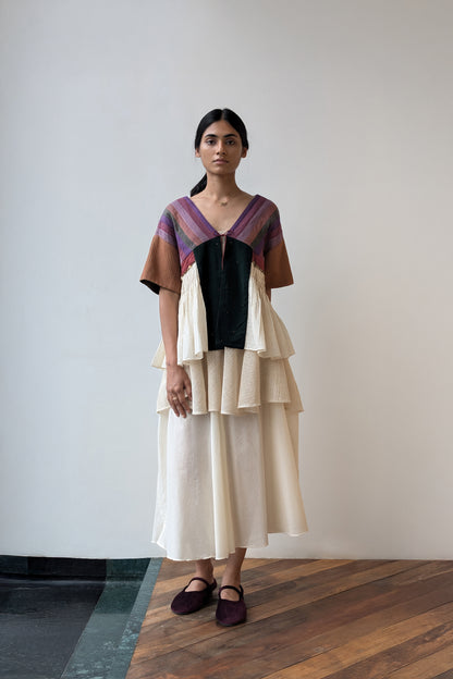 Woman wearing a layered dress with a geometric pattern against a plain background