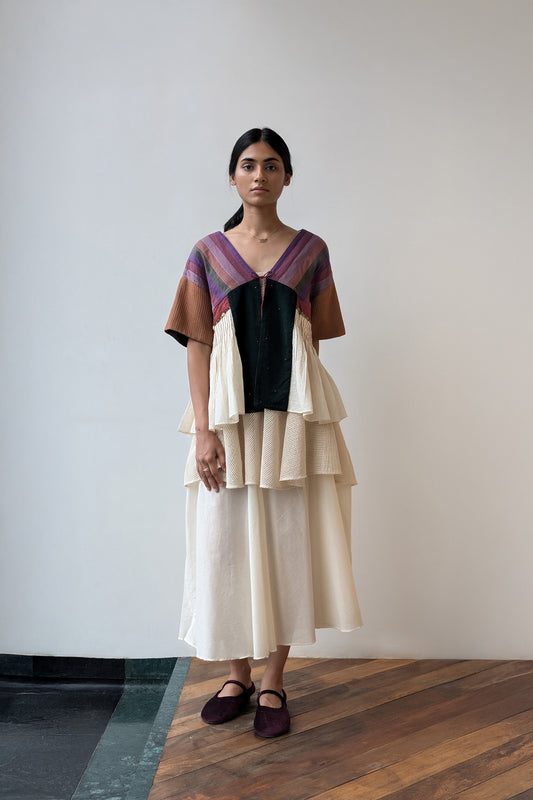Woman wearing a layered dress with a geometric pattern against a plain background